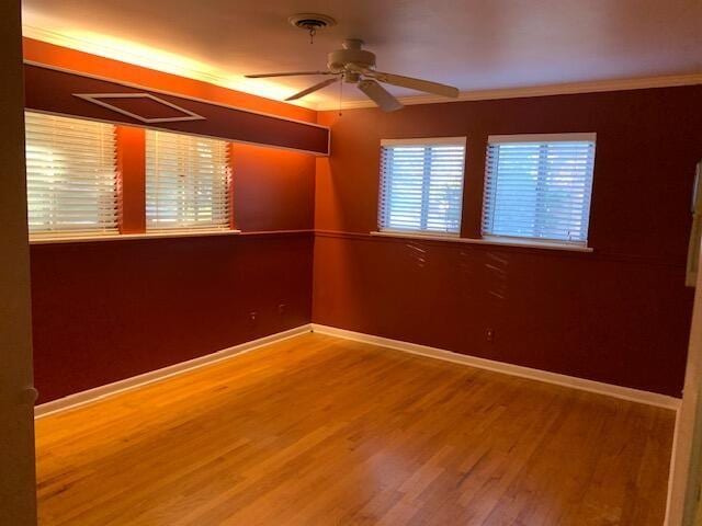 empty room with ceiling fan, wood-type flooring, and ornamental molding