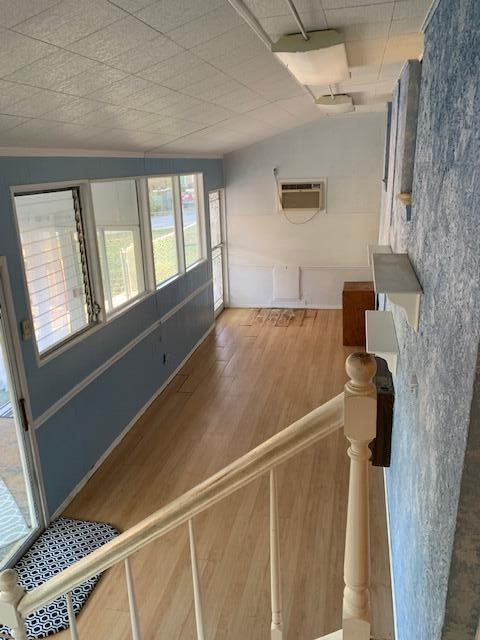 interior space with hardwood / wood-style flooring, an AC wall unit, crown molding, and vaulted ceiling