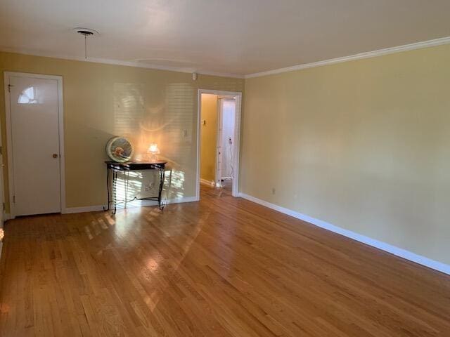 empty room featuring wood-type flooring and ornamental molding