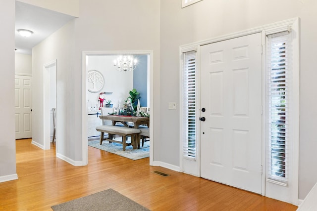 foyer entrance with a chandelier and wood-type flooring