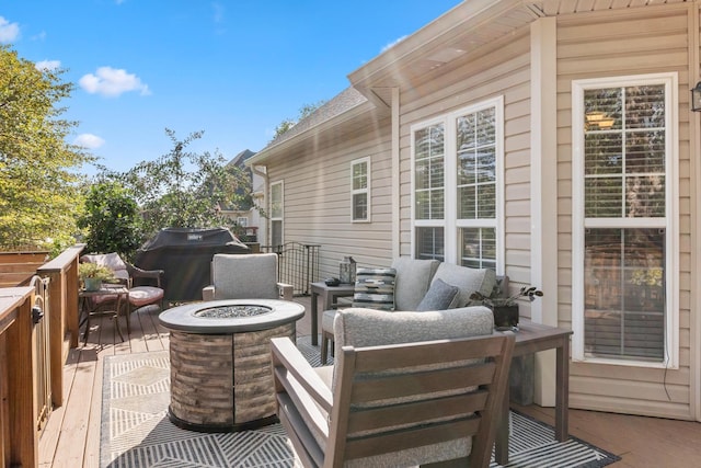 wooden terrace featuring a fire pit and a grill