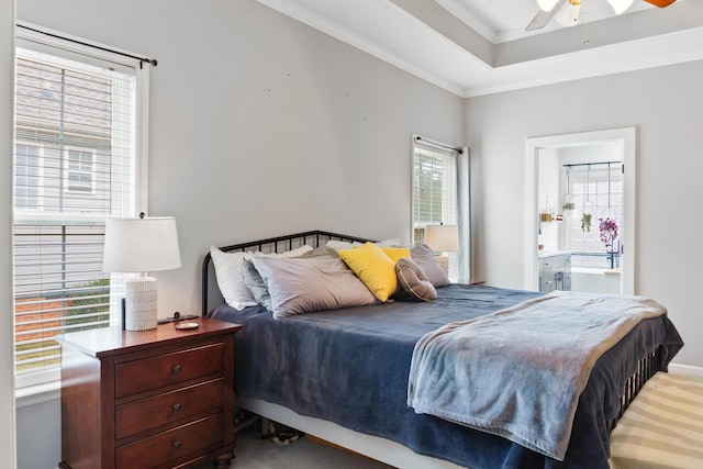 carpeted bedroom with a tray ceiling, ensuite bath, ceiling fan, and crown molding