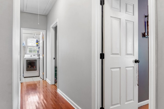 hallway with washer / clothes dryer and light hardwood / wood-style floors