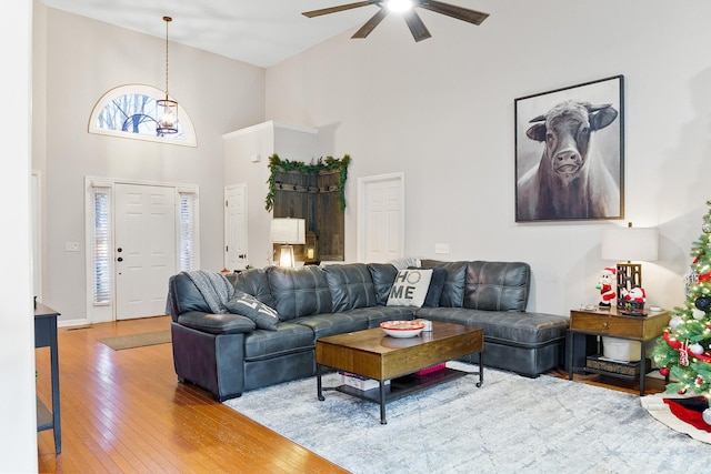 living room with ceiling fan, a towering ceiling, and wood-type flooring