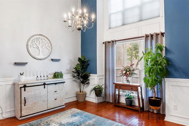 living area featuring a wainscoted wall, a decorative wall, wood finished floors, and an inviting chandelier