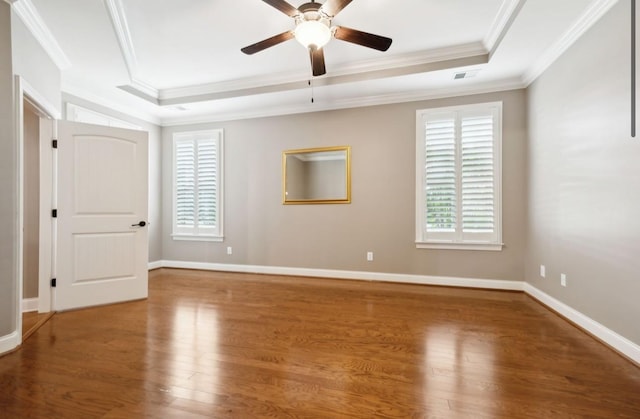 empty room featuring hardwood / wood-style flooring, a raised ceiling, ceiling fan, and crown molding