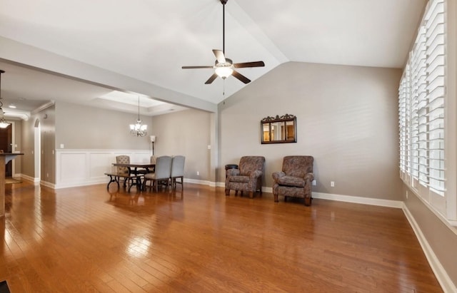 living area featuring wood-type flooring, ceiling fan with notable chandelier, and vaulted ceiling