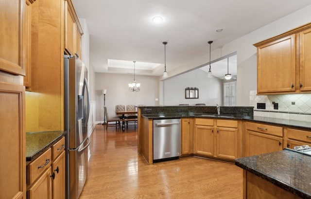 kitchen with ceiling fan with notable chandelier, sink, hanging light fixtures, appliances with stainless steel finishes, and kitchen peninsula