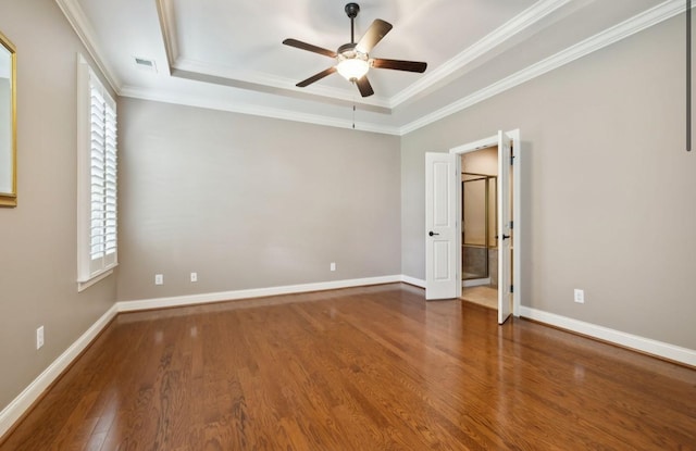 unfurnished bedroom featuring a tray ceiling, ceiling fan, dark hardwood / wood-style floors, and ornamental molding