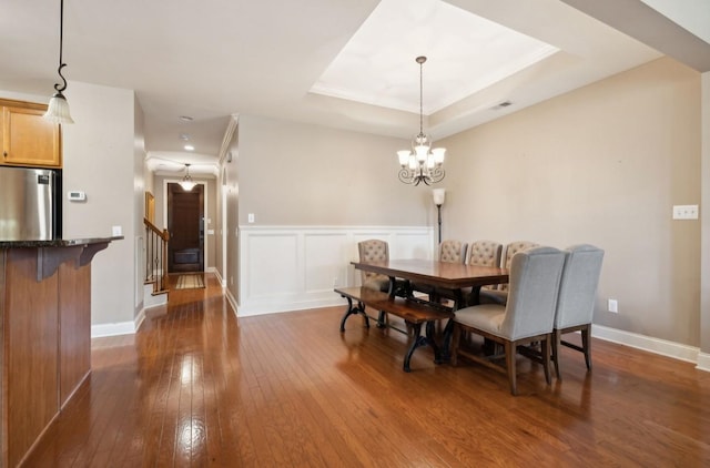 dining room featuring a notable chandelier, dark hardwood / wood-style floors, and a tray ceiling