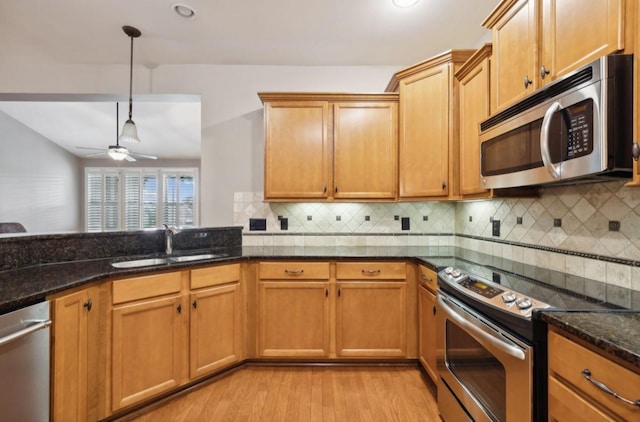 kitchen with pendant lighting, dark stone counters, ceiling fan, decorative backsplash, and appliances with stainless steel finishes