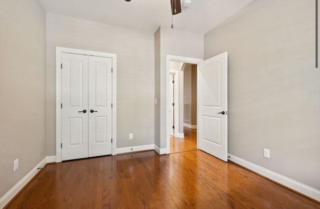 unfurnished bedroom featuring hardwood / wood-style floors, a closet, and ceiling fan