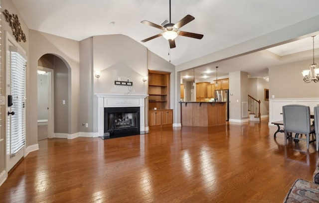 living room featuring built in shelves, dark hardwood / wood-style flooring, and ceiling fan with notable chandelier