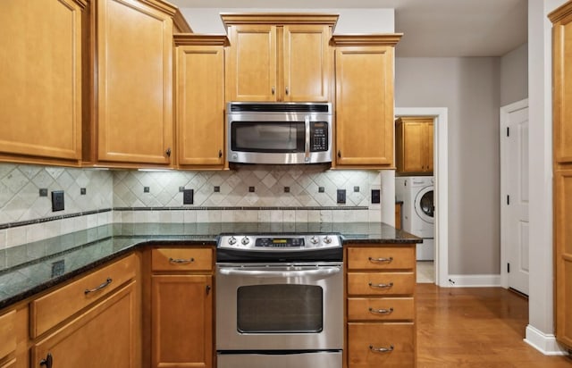 kitchen featuring appliances with stainless steel finishes, backsplash, washer / clothes dryer, and dark stone countertops