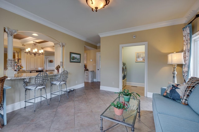 tiled living room with decorative columns, separate washer and dryer, a chandelier, and ornamental molding