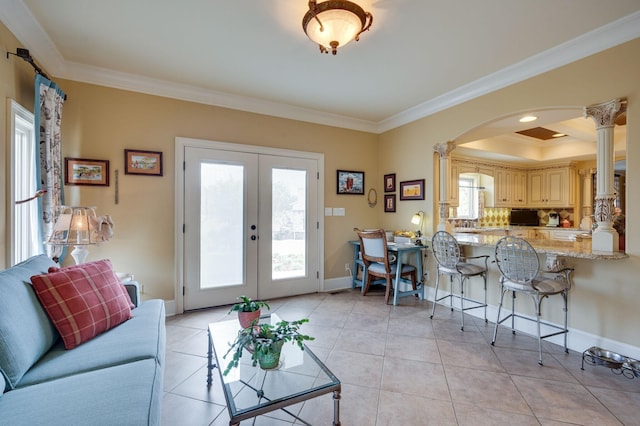 tiled living room with a tray ceiling, ornate columns, crown molding, and french doors