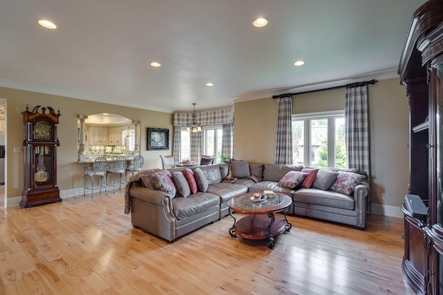 living room with light hardwood / wood-style floors, ornamental molding, and a chandelier