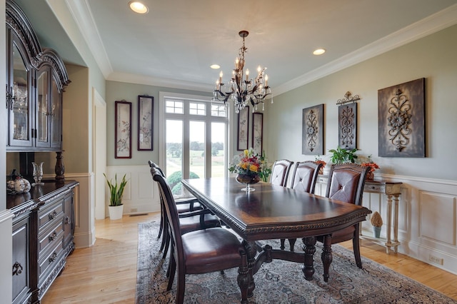 dining room with light hardwood / wood-style floors, crown molding, and an inviting chandelier