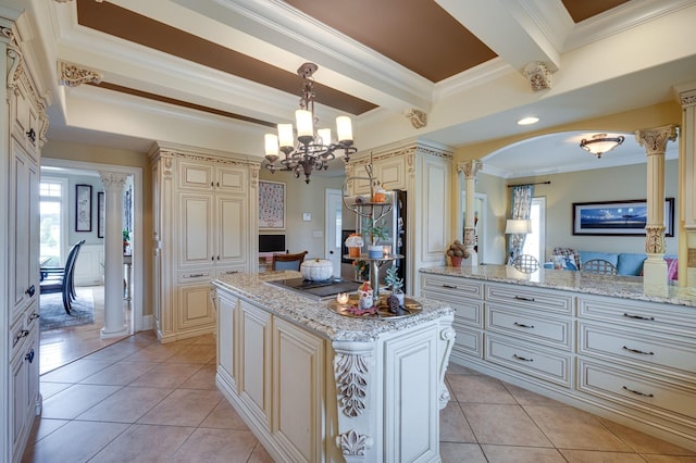 kitchen with ornate columns, crown molding, cream cabinets, and hanging light fixtures