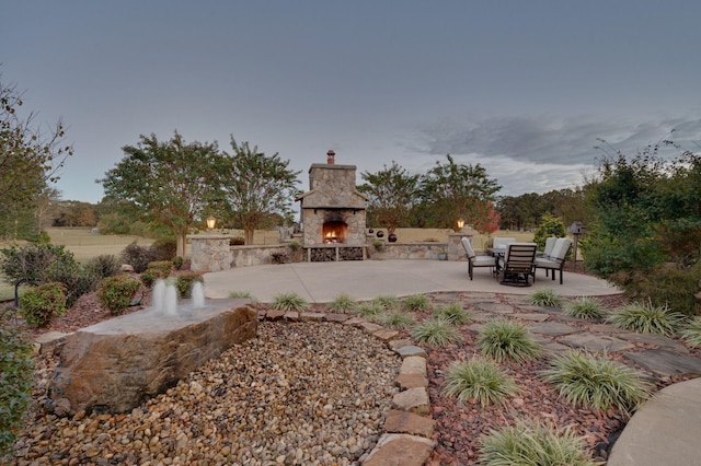 view of yard with an outdoor stone fireplace and a patio