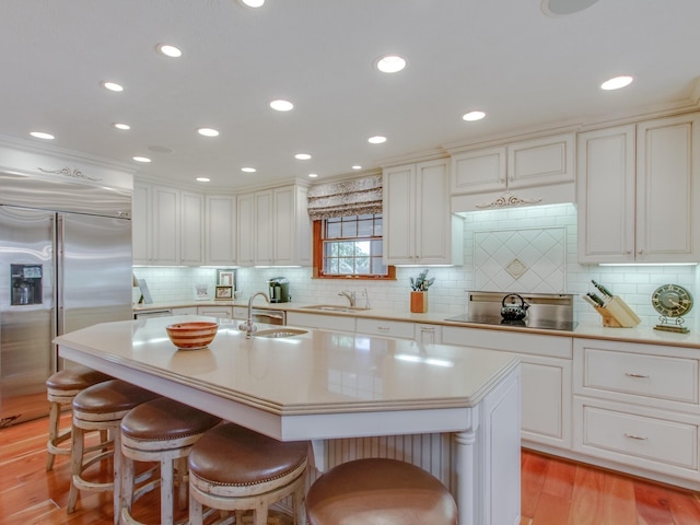 kitchen with a kitchen breakfast bar, a center island with sink, stainless steel built in fridge, and sink