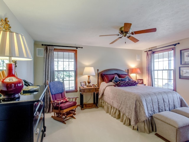 carpeted bedroom featuring ceiling fan and multiple windows