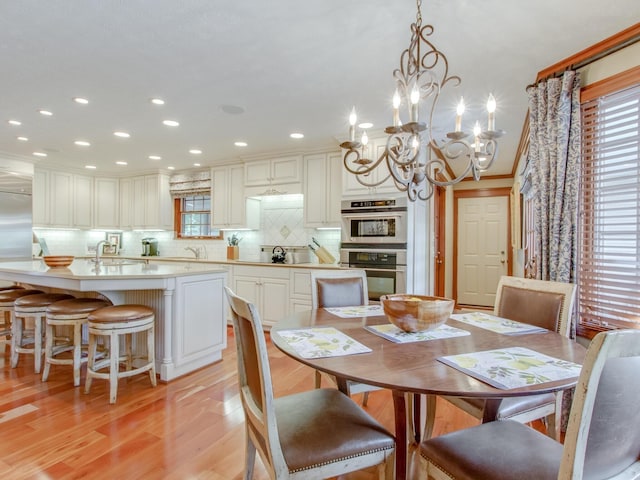 dining room featuring crown molding, sink, light hardwood / wood-style floors, and a notable chandelier