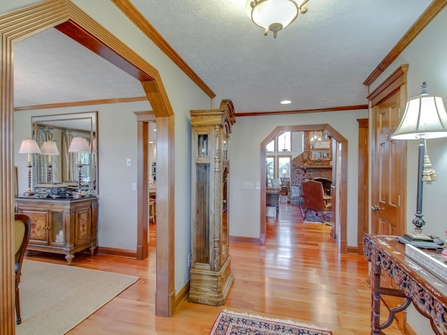 hallway featuring a textured ceiling, light hardwood / wood-style flooring, and ornamental molding