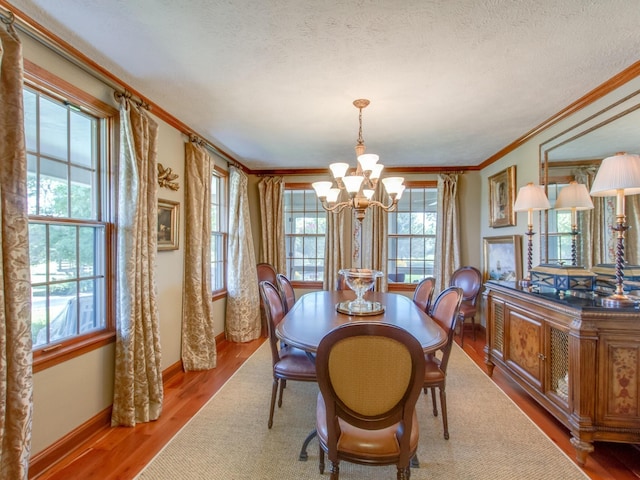 dining room with hardwood / wood-style flooring, ornamental molding, a textured ceiling, and a chandelier