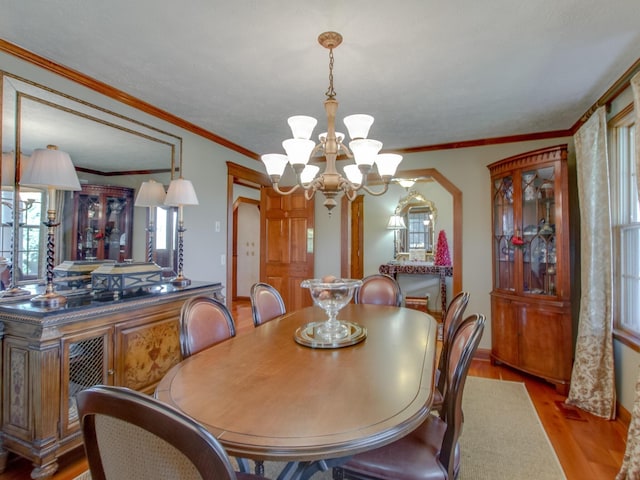 dining area with light hardwood / wood-style flooring, a chandelier, and ornamental molding