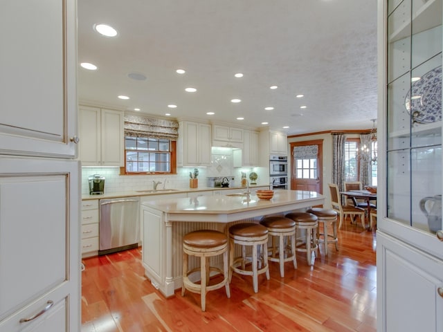 kitchen with a breakfast bar, sink, light wood-type flooring, appliances with stainless steel finishes, and a kitchen island