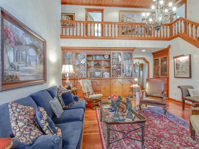 living room with a towering ceiling, light hardwood / wood-style flooring, a notable chandelier, and wood ceiling