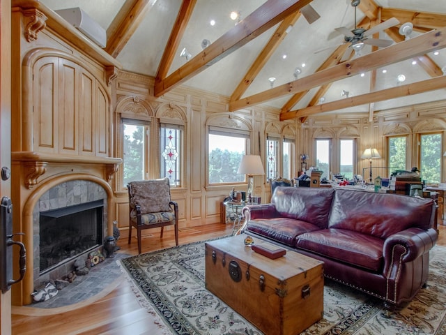 living room with a tiled fireplace, high vaulted ceiling, a healthy amount of sunlight, and hardwood / wood-style flooring