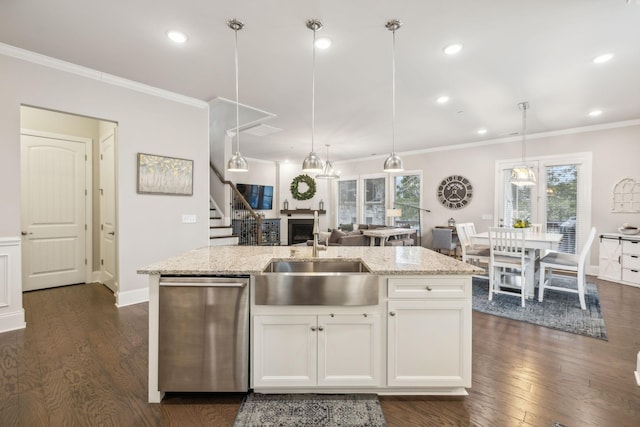 kitchen featuring sink, hanging light fixtures, stainless steel dishwasher, a center island with sink, and white cabinets