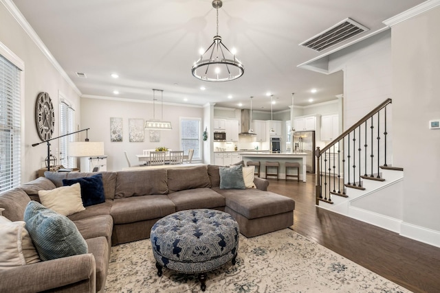 living room featuring ornamental molding, wood-type flooring, and an inviting chandelier