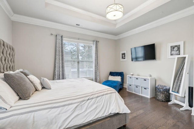 bedroom featuring a tray ceiling, crown molding, and dark wood-type flooring