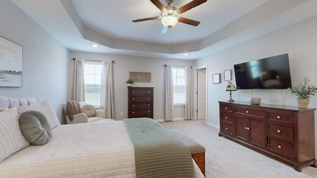 bedroom with a tray ceiling, ceiling fan, and light colored carpet