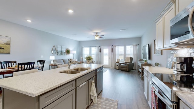 kitchen with a center island with sink, sink, ceiling fan, light hardwood / wood-style floors, and stainless steel appliances