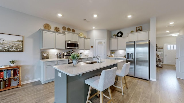 kitchen with sink, tasteful backsplash, a kitchen breakfast bar, a center island with sink, and appliances with stainless steel finishes