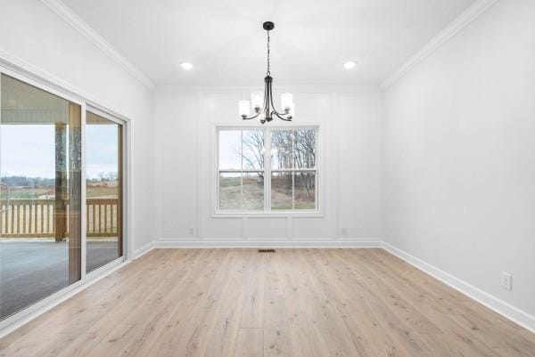 unfurnished dining area featuring light wood-type flooring, plenty of natural light, crown molding, and a notable chandelier