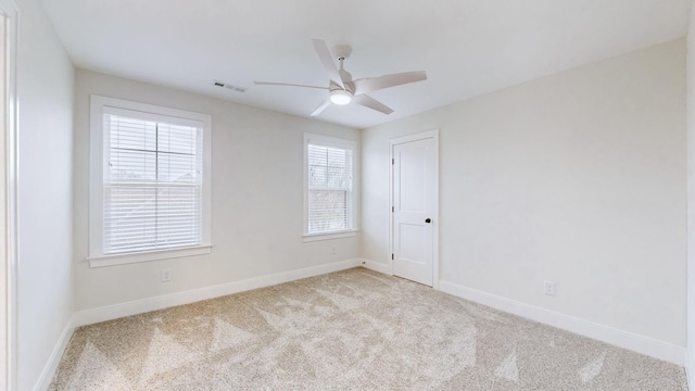 spare room with a wealth of natural light, ceiling fan, and light colored carpet