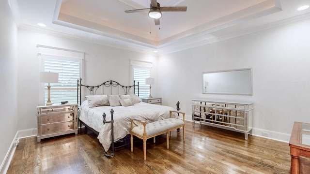 bedroom featuring ceiling fan, a raised ceiling, and multiple windows