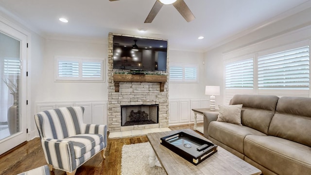 living room featuring a fireplace, crown molding, ceiling fan, and dark wood-type flooring