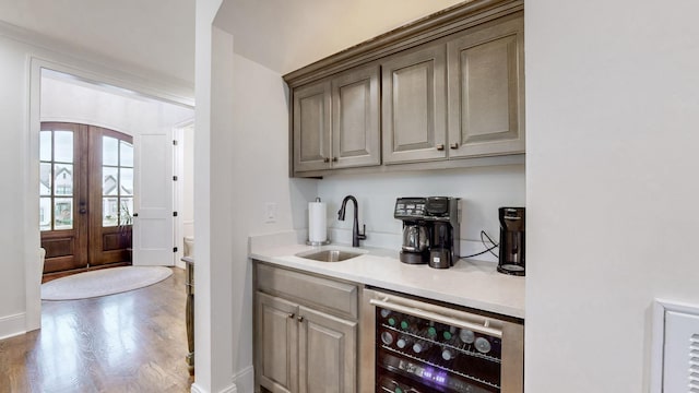 bar featuring wood-type flooring, sink, beverage cooler, and french doors