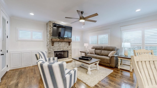 living room with crown molding, a fireplace, ceiling fan, and dark wood-type flooring