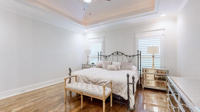 bedroom with dark hardwood / wood-style floors, a raised ceiling, ceiling fan, and crown molding