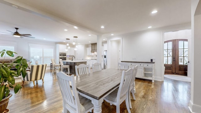 dining room with french doors, sink, ceiling fan, light wood-type flooring, and beamed ceiling