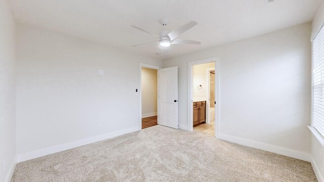 unfurnished bedroom with light carpet, ensuite bath, and ceiling fan