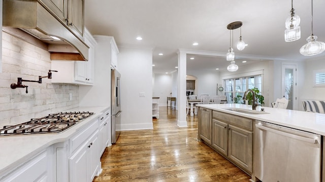 kitchen with backsplash, stainless steel appliances, sink, white cabinetry, and hanging light fixtures