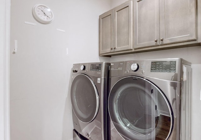 laundry room featuring washer and dryer and cabinets